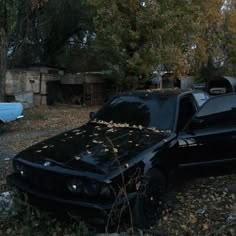 a car that is sitting in the grass with leaves on it's hoods