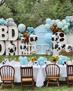 a table set up with balloons and decorations for a cow themed baby shower or birthday party