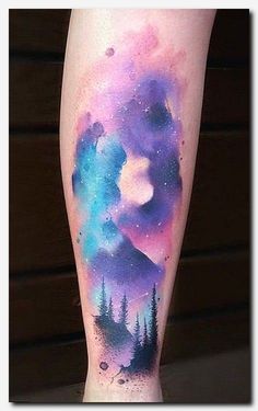 a woman's leg with a watercolor painting on it and trees in the background