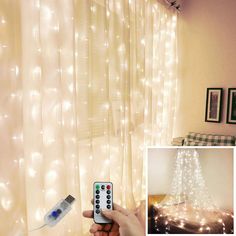 a hand holding a remote control in front of a curtain with lights on it and a bed