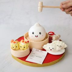 a person is holding a chopstick over small bowls with food in them on a red tray