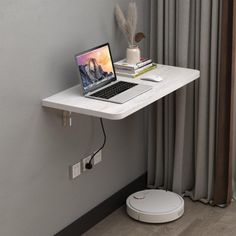 a laptop computer sitting on top of a white table next to a window with curtains