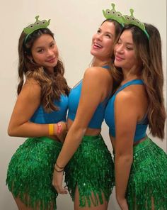 three young women in green and blue outfits posing for the camera with their arms around each other