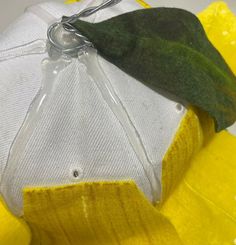 a green leaf on top of a white and yellow object with some silver wire attached to it