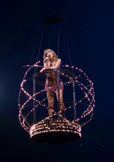 a woman standing on top of a metal structure with lights all around her and in the air