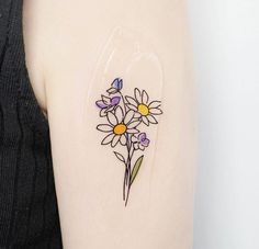 a woman with a tattoo on her arm has flowers painted on the back of her arm