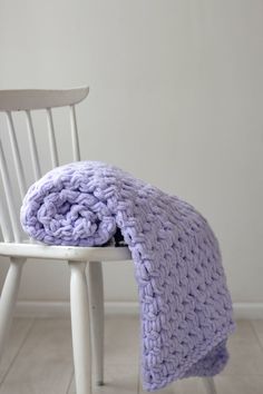 a purple knitted blanket sitting on top of a white chair