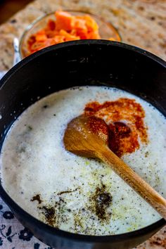 a wooden spoon in a pot filled with milk and other food items on a table