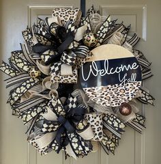 a welcome sign is hanging on the front door with leopard print and black ribbon around it