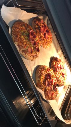 three pizzas sitting in an oven on top of white paper under the burners