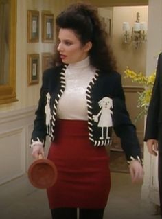 a woman in a skirt and jacket holding a frisbee while standing next to another man