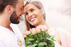 a man holding a bouquet of pink roses next to a smiling woman with her eyes closed