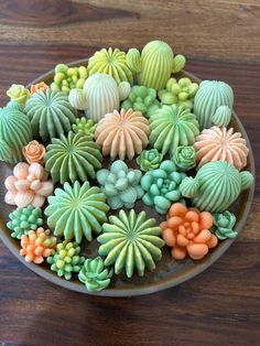 a bowl filled with green and orange fake succulents on top of a wooden table