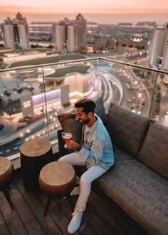 a man sitting on top of a couch next to a table with a drink in it