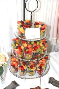 a tiered cake with lots of fruit on top and silverware next to it