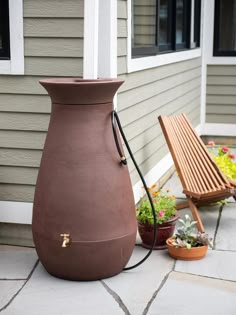 a large brown vase sitting on top of a patio next to a wooden bench and potted plants