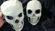 two white skulls with black eyes are being held up