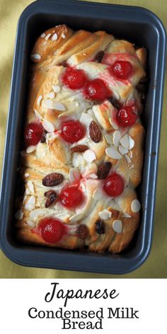 a loaf of bread topped with cherries and almonds in a baking pan on a table