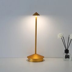 a lamp that is next to a vase with flowers in it on a white table