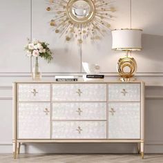 a white and gold dresser in a room with flowers on the sideboard next to it