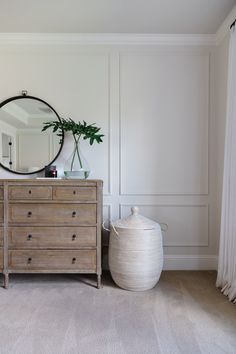 a dresser and mirror in a room with white walls