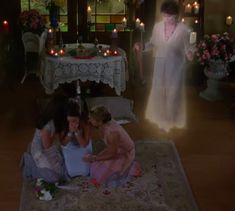 three women sitting on the floor in front of a table with candles and flowers around it