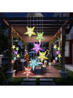 colorful stars hanging from the ceiling in front of a house at night with lights on