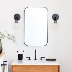 a bathroom with a sink, mirror and vase on the counter top in front of it