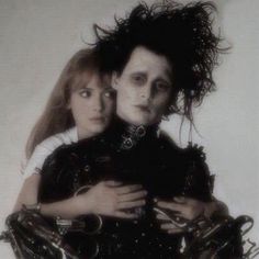 two people dressed in black and white posing for the camera with their arms around each other