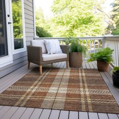 an outdoor area rug on a deck with chairs and potted plants next to it