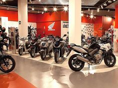 several motorcycles are on display in a showroom with red walls and white ceilinging