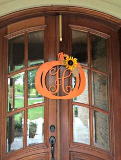 an orange monogrammed door hanger with a sunflower on it