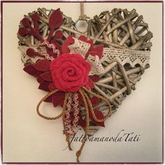 a heart shaped decoration made out of wood sticks and lace with a red rose on top