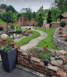 a garden with lots of plants and flowers on the ground next to a brick wall