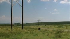 a car driving down a road next to power lines and telephone poles in the distance