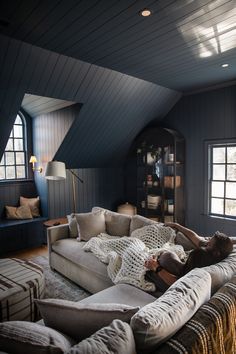 a woman laying on top of a couch in a living room next to a window