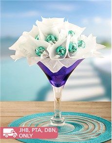 a glass vase filled with white flowers on top of a wooden table next to a blue place mat