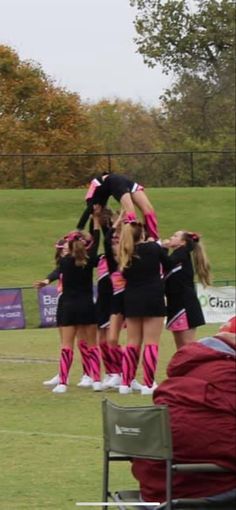 a group of cheerleaders standing on top of each other in the middle of a field