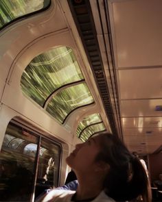 a woman sitting on a bus with her eyes closed and looking up at the ceiling