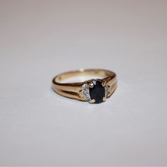 a close up of a ring on a white surface with a black diamond in the middle