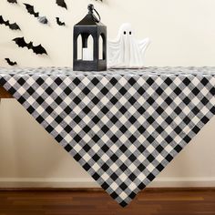 a black and white checkered table cloth on a wooden table with halloween decorations in the background