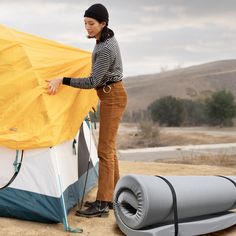 a woman standing next to a tent and sleeping bag