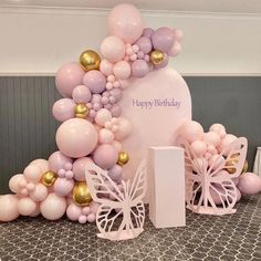 pink and gold balloon arch with butterflies on it for a birthday party or baby shower