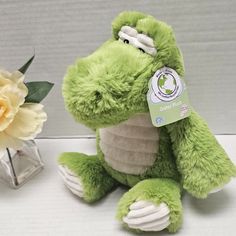 a green stuffed animal sitting next to a flower