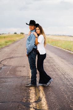 a man and woman standing in the middle of an empty road with their arms around each other