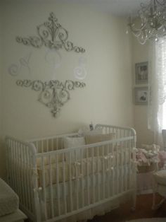 a white crib in front of a chandelier