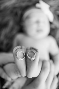 a woman holding a baby's hand with two rings on her thumb in the air