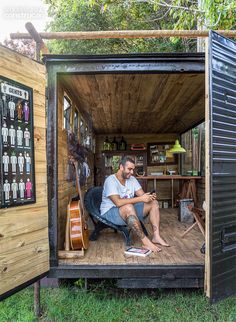 a man sitting in the back of a small shed on top of a wooden floor