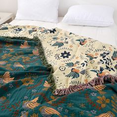 an unmade bed with blue and orange floral bedspread on top of it