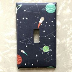 a light switch cover with outer planets and stars on it, sitting on a table